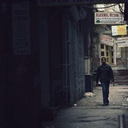 A child walking down a deserted lane in an Indian town.